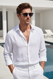 Man wearing a white shirt and pants with Pas Jalou sunglasses, standing by a pool.