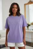 Woman wearing a purple t-shirt with embossed "pas jalou" text.