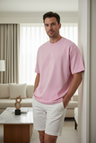 Man wearing a pink t-shirt with embossed text "PAS JALOU"