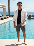 Man standing by a pool wearing a white shirt, black shorts, and pas jalou sunglasses with a scenic background.