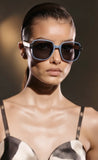 Model wearing a stylish outfit with pas jalou sunglasses against a dark background