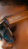 Sunglasses with 'PAS JALOU' branding on a close-up of a person wearing them.