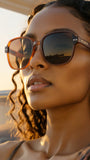 Woman wearing Pas Jalou sunglasses with a blurred sunset background
