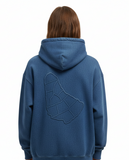 Person wearing a blue hoodie with a geometric design of the map of barbados on the back, on a white background