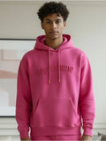 Person wearing a pink hoodie with '#goodtime' text indoors