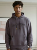 Person wearing a  ash purple hoodie with '#agoodtime'  embossed text in a neutral indoor setting