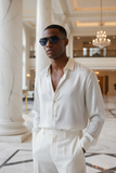 Man wearing a white outfit with Pas Jaloun sunglasses in an elegant interior setting