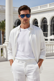 Man wearing a white outfit with Pas Jalou sunglasses in front of a classical building.