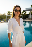 Woman in a white outfit standing by a pool with pas jalou sunglasses on