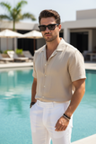 Man wearing sunglasses and a beige shirt by a poolside