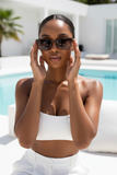 Woman wearing Pas Jalou sunglasses and a white outfit by a pool