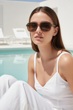 Woman wearing Pas Jalou sunglasses by a poolside
