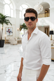 Man wearing pas jalou sunglasses and a white shirt in an elegant indoor setting