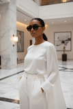 Woman in a white outfit and sunglasses from pas jalou,standing in an elegant interior setting