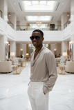 Man wearing pas jalou sunglasses and a light-colored shirt in a large, open indoor space with high ceilings.