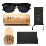 Classic black sunglasses with dark lenses, displayed with a bamboo case and accessories