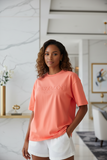 Woman wearing a coral t-shirt with text in a modern indoor setting