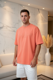 Man wearing a coral t-shirt with text in a modern indoor setting