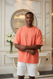 Man wearing a coral t-shirt with text in an elegant interior setting