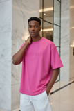 Man wearing a pink t-shirt with '"PAS JALOU"  