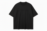 Black t-shirt with embossed text "PAS JALOU'  on a white background