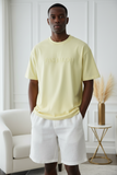 Man wearing a light yellow t-shirt with "pas jalou" embossed text.