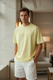 Man wearing a light yellow t-shirt with "pas jalou" embossed text