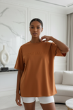 Woman wearing a brown t-shirt with embossed "pas jalou" text
