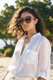 Woman wearing sunglasses and a white shirt on a beach