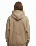Person wearing a khaki hoodie with a geometric embossed design of the map of barbados on the back of the sweater